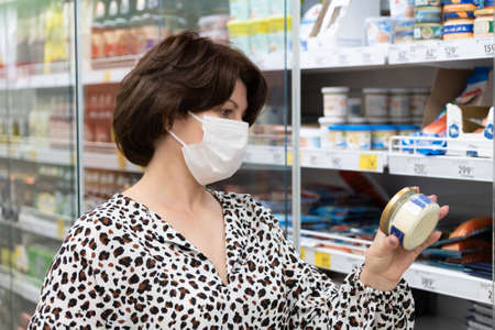 Portrait of a woman in a medical mask chooses products in the storeの写真素材