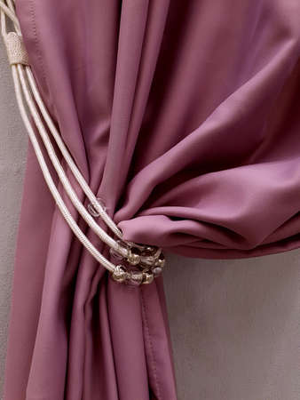 Fragment of beautiful pink curtains with holder