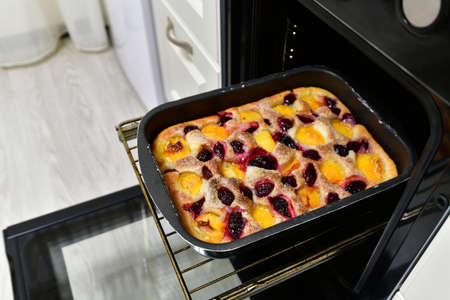 Baked cherry, apricots, plums pie on a baking sheet in the ovenの写真素材