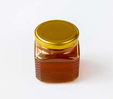 Honey in a glass jar on a light backgroundの写真素材