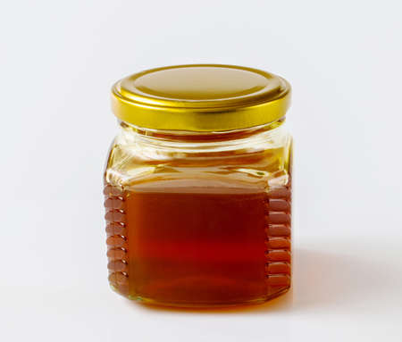 Honey in a glass jar on a light backgroundの写真素材