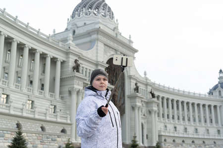 boy does selfie on phone with self-stick against backdrop landmark buildingの写真素材