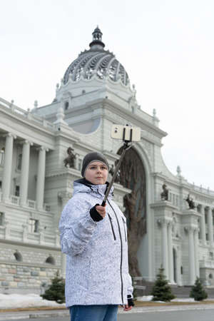boy does selfie on phone with self-stick against backdrop landmark buildingの写真素材