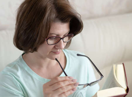 Woman with impaired vision reading a book through two glassesの写真素材