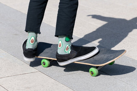 legs of teenager in green socks on a skateboard