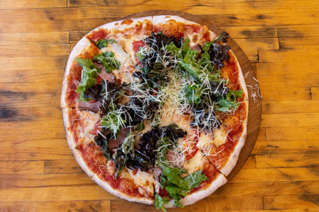 Pizza with ham and salad on a wooden tableの写真素材