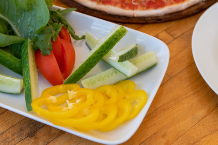 a plate of fresh vegetables - tomato, cucumber, yellow pepper and saladの写真素材