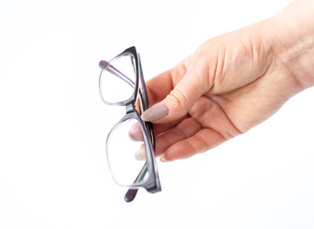 Glasses for vision correction in a female hand on whiteの写真素材