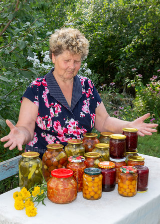 Cheerful woman with homemade canned vegetables in gardenの写真素材