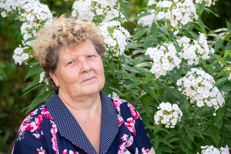 Portrait of a woman 60s years old against the background of flowers in the gardenの写真素材