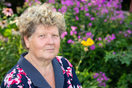 Portrait of a woman 60s years old against the background of flowers in the gardenの写真素材