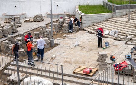 Moscow, Russia - June 17. 2022. Workers laying tiles on a sidewalk