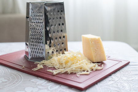 A pile of grated cheese on a plastic board next to a graterの写真素材