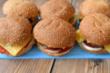 Several homemade burgers on a plastic cutting board and wooden backgroundの写真素材