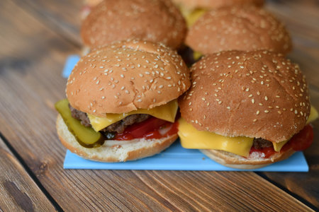 Several homemade burgers on a plastic cutting board and wooden backgroundの写真素材