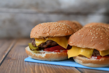 Several homemade burgers on a plastic cutting board and wooden backgroundの写真素材