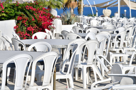 Outdoor cafe with white plastic tables and a chairsの写真素材