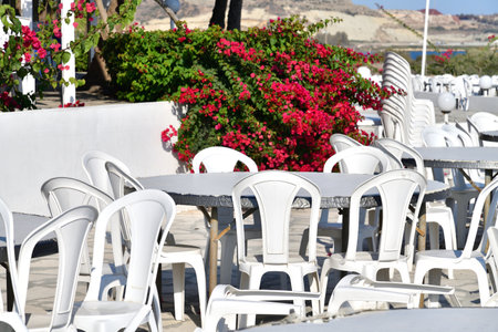 Outdoor cafe with white plastic tables and a chairsの写真素材