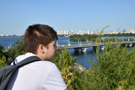 A teenager with a backpack looks on the river in Russiaの写真素材