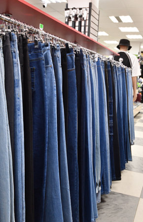 Jeans hanging on hanger in a storeの写真素材