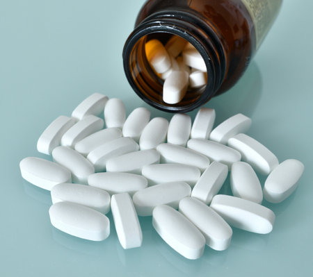 White large pills and glass bottle on blue backgroundの写真素材