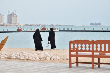 women in national clothes on embankment of city beach in Doha, Qatar