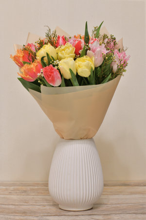 A bouquet of flowers in a ceramic vase stands on a table in the roomの写真素材