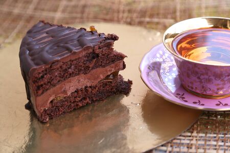 A piece of cake with chocolate filling and a cup of teaの写真素材