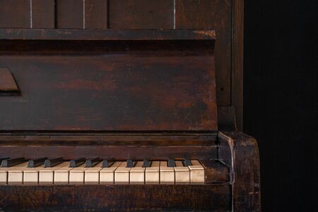 A part of old wooden piano keys on wooden musical instrument in front view on black backgroundの写真素材