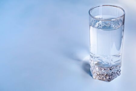 A glass of clean water on an empty blue tableの写真素材