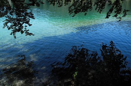 Wonderful beauty of great Germany Nature. Mountain lake Alpsee with blue and green turquoise colored deep clean water surface. Shadow and light diagonal areas. Moments of journey.の写真素材
