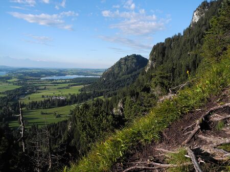 Panoramic photo of beautiful german land nature. Trees, lakes, meadows, fields from bird's-eye flight view. Scenic tourist route on the Alpine mountains. Mood of freedom, activity, journey, adventure.の写真素材