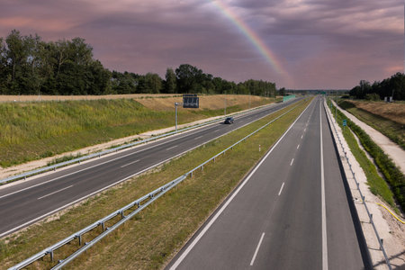 Asphalt road with a rainbow in the sky. Landscape.の写真素材