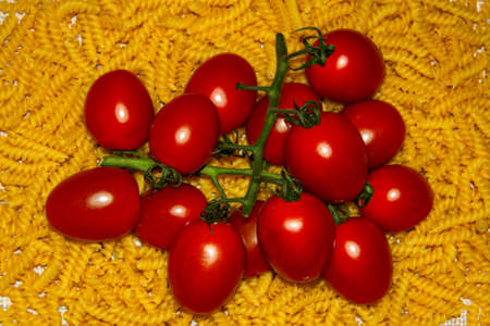 Red tomatoes on the background of GIRANDOLE paste. Preparation for cooking pasta with tomato sauceの写真素材