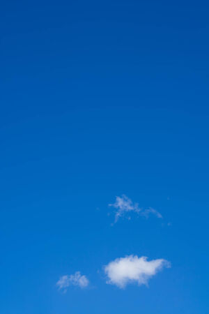 bright blue sky with small white clouds backgroundの写真素材