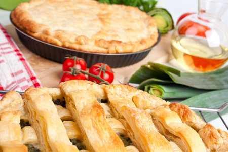 two pies - open and closed with tomatoes, leek and oil at the backの写真素材