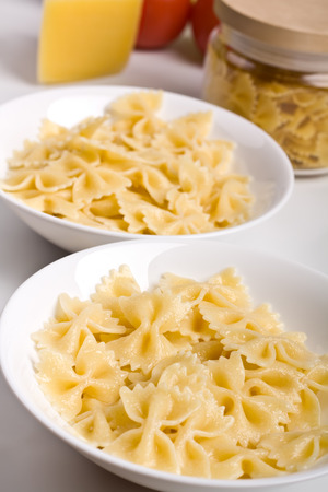 bowls with cooked pasta and raw pasta and cheese at the backの写真素材