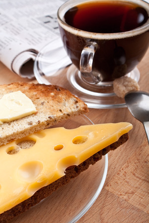 breakfast with coffee, cheese and butter on toast and a newspaperの写真素材