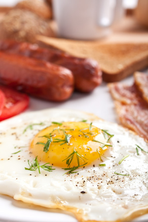 classic breakfast with fried egg, sausages, bacon and toastの写真素材