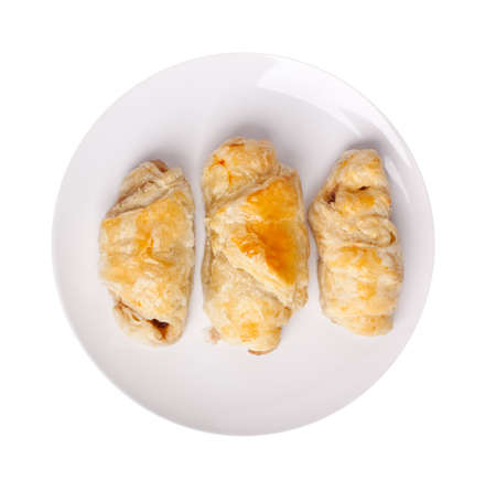 three sausage rolls on a white plate with more rolls at the background on dark platesの写真素材