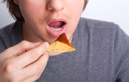 young man eating nachos close upの写真素材
