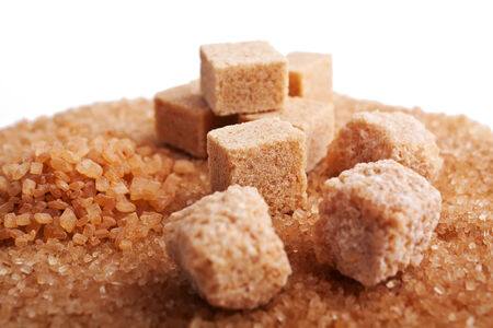 brown sugar cubes isolated on sugar crystals backgroundの写真素材