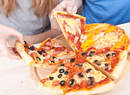 two young people eating pizzaの写真素材