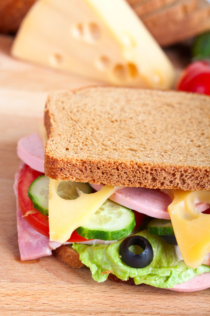 big sandwich - cheese, meat and vegetables with ingredients at the backの写真素材