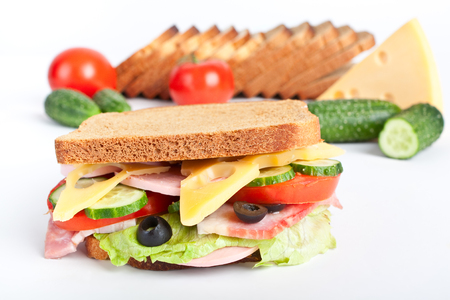 big sandwich - cheese, meat and vegetables with ingredients at the backの写真素材