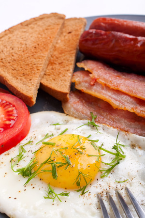 classic breakfast with fried egg, sausages, bacon and toastの写真素材