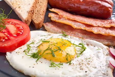 classic breakfast with fried egg, sausages, bacon and toastの写真素材
