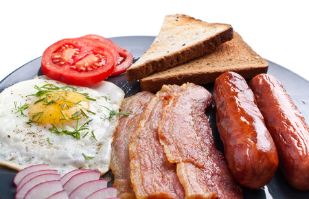 classic breakfast with fried egg, sausages, bacon and toastの写真素材