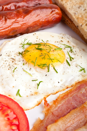classic breakfast with fried egg, sausages, bacon and toastの写真素材