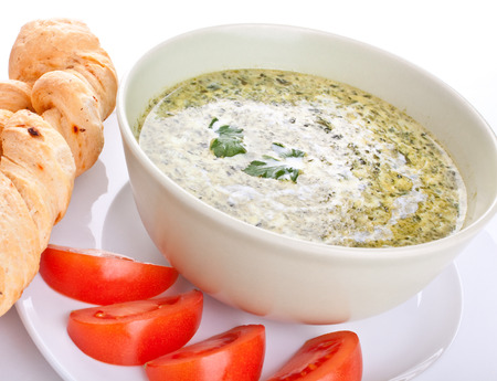 spinach cream soup with bread and tomatoesの写真素材